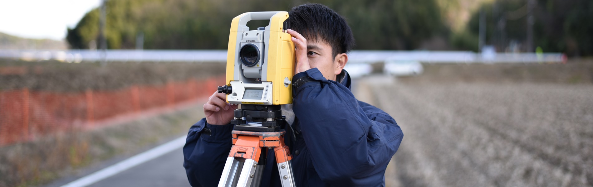 現地で測量機器をのぞき込む測量士